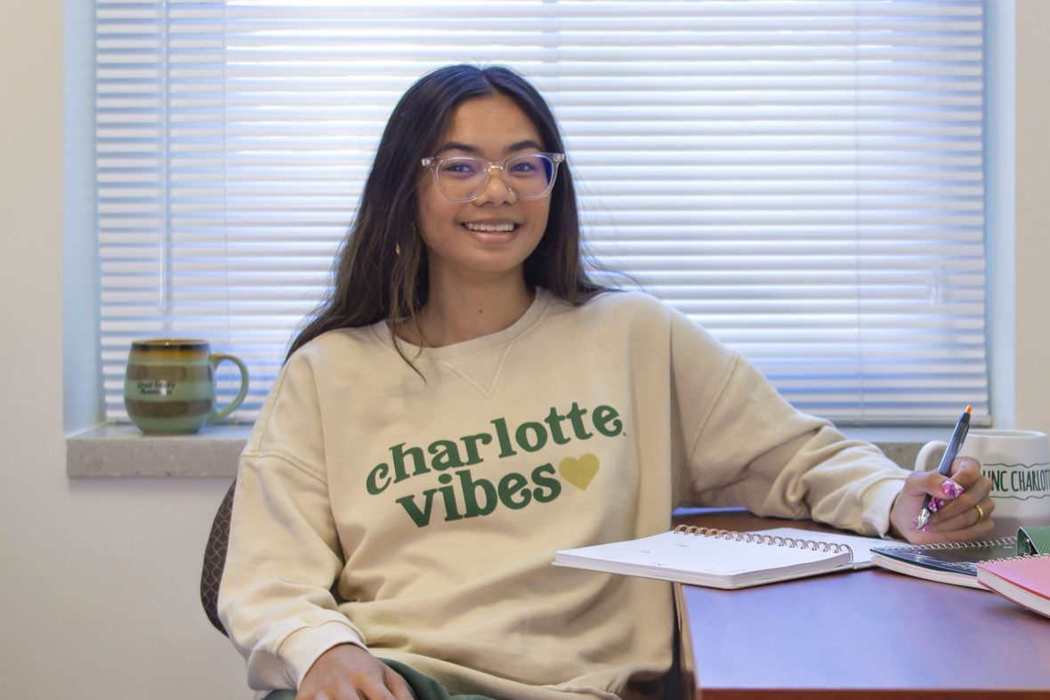 Student at dorm desk smiling at camera.