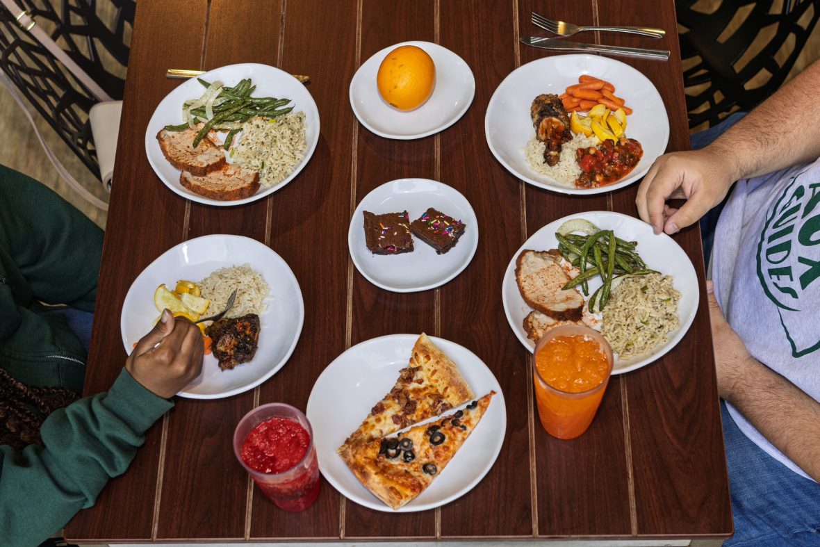 Assortment of plates of food from the SoVi dining hall, like pizza, brownies, fruit and veggies.