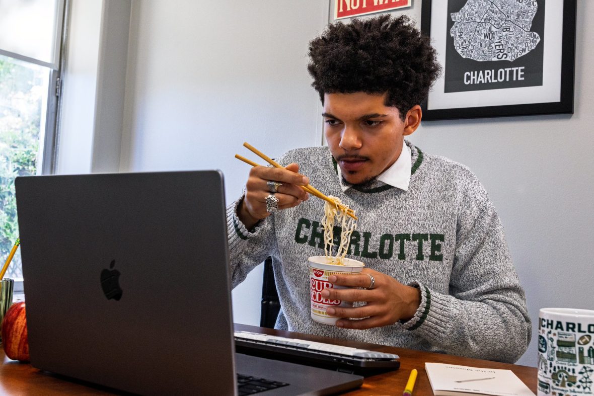 Student looking at computer while eating instant noodles