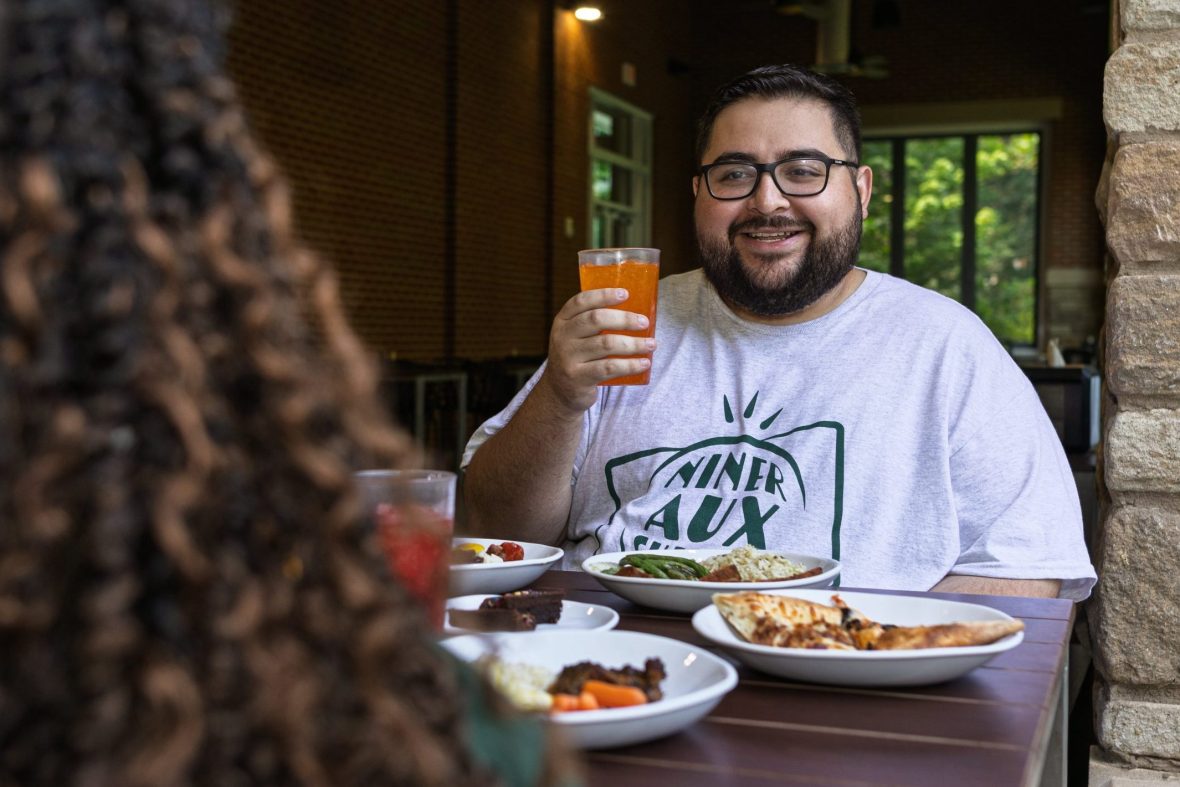 Students eating inside dining hall, one with back to camera