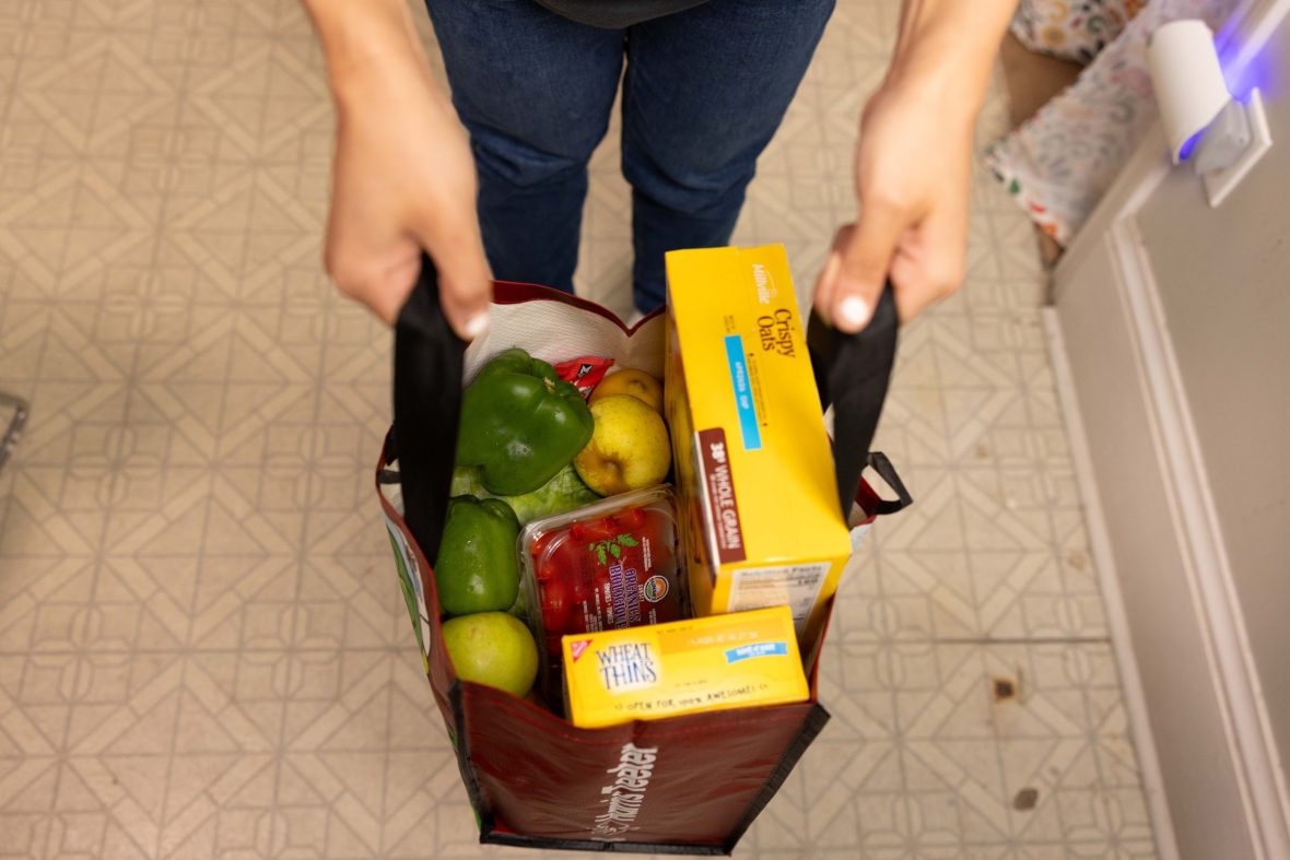 Hands holding bag of fresh and pantry items