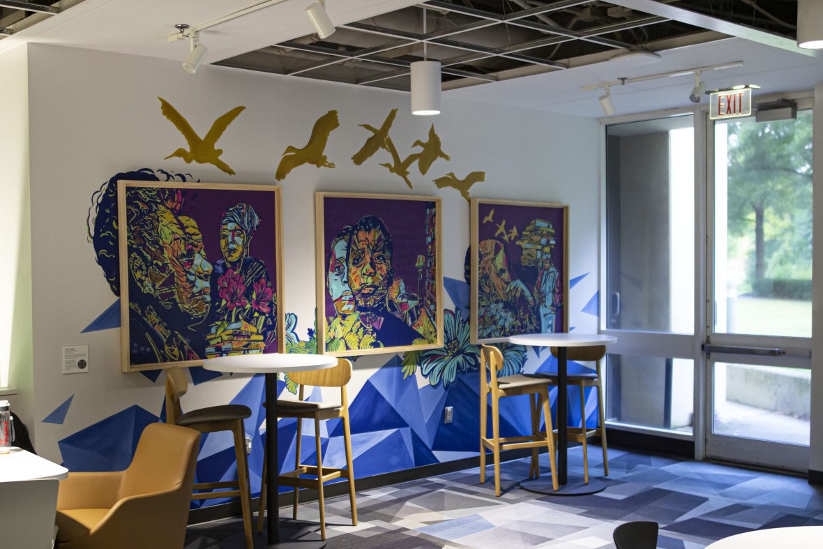 Purple and blue murals framed on wall in front of tables with decals of gold birds above