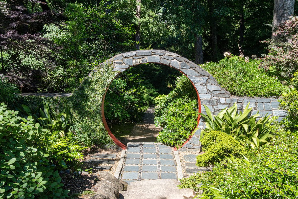 stone arch between plants with a path going through