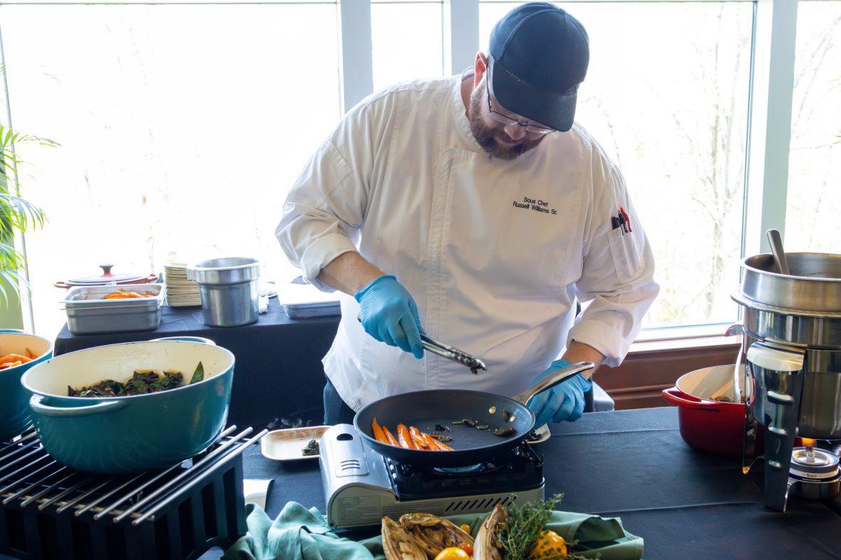 Chef adding vegetables to pan
