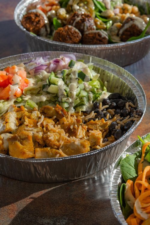 halal bowl with chicken and vegetables, surrounded by two other bowls